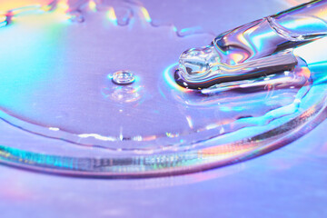 Pipette with sample of cosmetic product in petri dish on holographic background, iridescent...