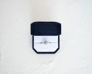 Top view of a beautiful diamond engagement ring in a blue velvet box on a white surface