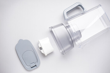 A disassembled jug for filtering water on a grey background, top view.