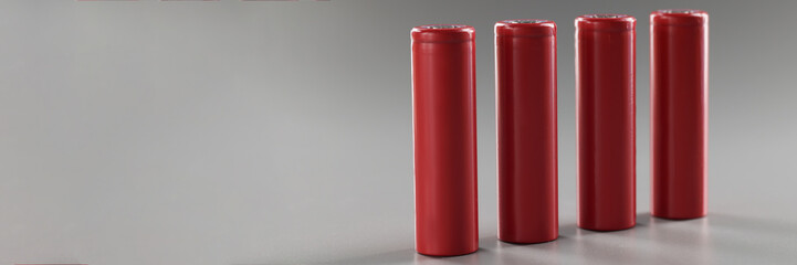 Red alloy batteries stand in a row on a gray background