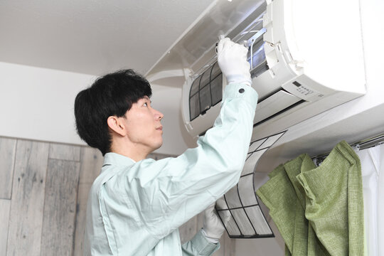 家庭用エアコンを調査する男性作業員