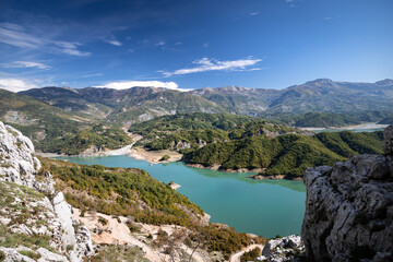 Fototapeta na wymiar The water reservoir Lake Bovilla surrounded by mountains, blue sky, in Albania