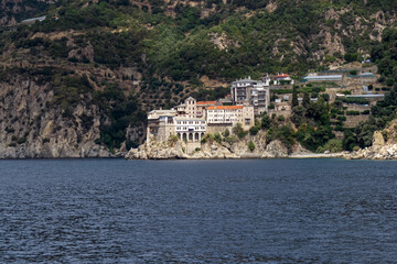 Scenic view from boat on Osiou Gregoriou Monastery at Mount Athos, Chalkidiki, Central Macedonia, Greece, Europe. Eastern Orthodox terrain of Again Oros. Landmark build on coastline rock formation