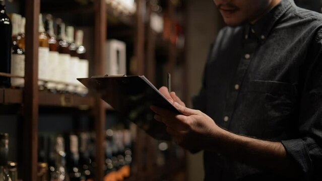Night club concept of 4k Resolution. The bartender is checking the merchandise in the store. A group of specialized clubs that sell alcoholic beverages.