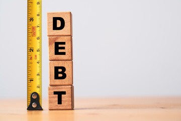 Debt wording stacking on wooden block cube with yellow tape measurement for debt analysis concept.