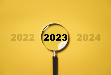 2023 year inside of magnifier glass among 2022 and 2023 for focus and concentrate of new business...