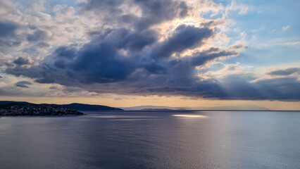 Fototapeta na wymiar Early morning view of the sunrise over the Mediterranean Aegean Sea. View on the peninsula Mount Athos (Again Oros), Chalkidiki, Central Macedonia, Greece, Europe. Sun beams on the water surface, calm