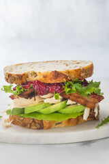 Close up of a turkey and bacon club sandwich with cranberry sauce and avocado.