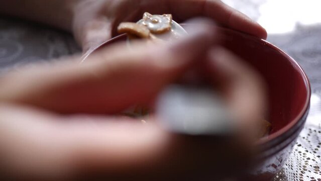 Close up of hand with spoon eating cinnamon sugar cereal from bowl