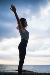 A woman with arms up performing yoga exercises.