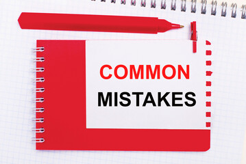 On a white notepad, a red pen, a red notepad and a white sheet of paper with the text COMMON MISTAKES