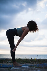 Side view of woman performing yoga exercises in a natural setting.