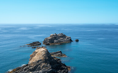 Formación de rocas adentrándose en las aguas del mar Mediterráneo en la villa costera de Almuñecar, España