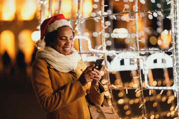 Black Woman Using Smartphone In The City At Christmas Time