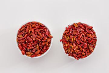 Dried Barberry berries in round ceramic white plates, top view on table. Ripe dry sour-tasting berries, healthy seasoning for food. Red Barberry natural food. Healthy and tasty spice