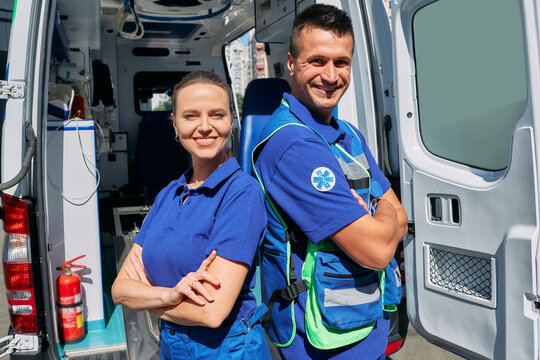 Ambulance medical staff. Portrait of paramedics team standing near their ambulance vehicle with crossed arms and looking at camera