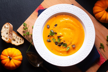 Food concept Organic pumpkin soup on wooden board and black slate stone background with copy space