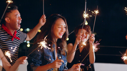 Group of young Asian people with friends celebrating party on rooftop holding sparklers fireworks and enjoy together