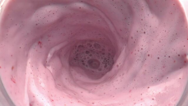Fruit milk cocktail rotating moving top view. Calcium milkshake making funnel