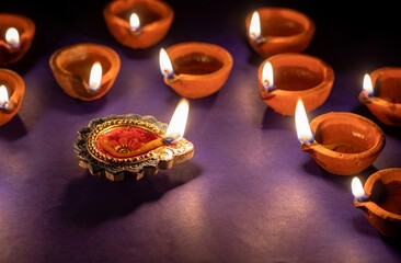 Happy Diwali or Deepavali Festival Diya with Glowing Lit Flame or Oil Lamp Isolated on Blue Background, Deepavali or Diwali Festival Celebration Concept, Festival of Lights