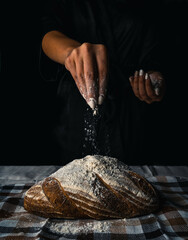 The female hands in flour and rustic organic loaf of bread
