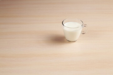 Milk in a Transparent Mug on a Table. White Beverage in a Glass Cup on a Wooden Table