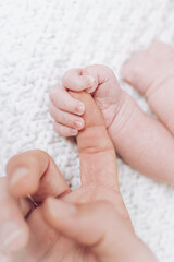 baby holds mom's finger very tightly in detail