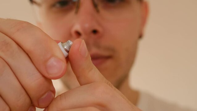 Man with herpes on lips against light grey background. Cold sore on a man lips. Sore virus concept. Man touch sore by fingers and use cream for treatment and therapy sore. Man spread white cream on a