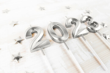 Numerals 2023 in silver color on a wooden background close-up. Christmas card in a minimalist style.