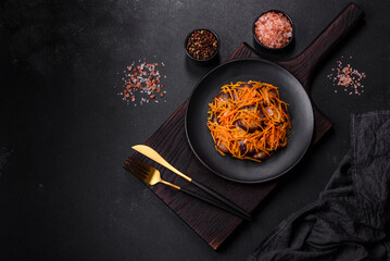 Korean salad with eggplant, carrots, garlic, spices and herbs on a dark concrete background