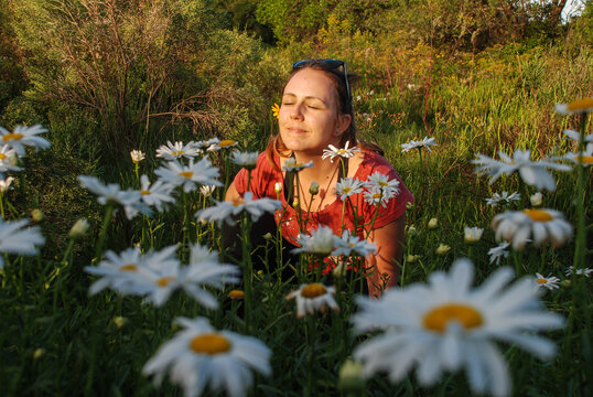 Blonde Young Woman With Sunglasses On Top Of Head And Eyes Closed Smiling On A Chamomile Flower Field In A Beautiful Sunny Day