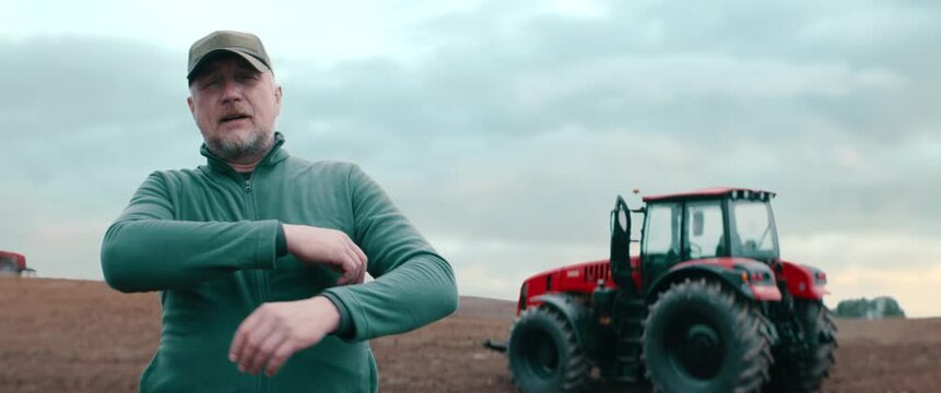 Hero shot portrait of 50s farmer posing against tractor early in the morning in the field. Shot with 2x anamorphic lens