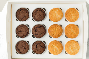 Set of brown chocolate and white vanilla cupcakesin the white gift box. Flat lay