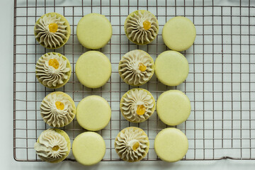 A lot of green macaroon halves on a cooling rack with matcha tea ganache filling. Сooking process of French dessert macaroon. Flat lay