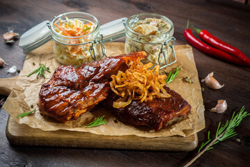 Two steaks with barbecue sauce fried onions and two glass jars of coleslaw and apple celery salad.