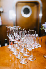 A lot, a row of empty transparent wine glasses stands on a wooden table in a bar, cafe close-up.