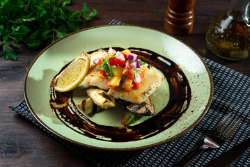 Cod fillet with salsa sauce and a slice of lemon on grilled eggplant halves.