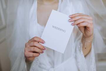 The bride in her hands holds a white envelope, an invitation, a gift sheet of paper. Close-up wedding photography, copy space.