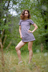 Slim young woman posing in a short dress outdoors.