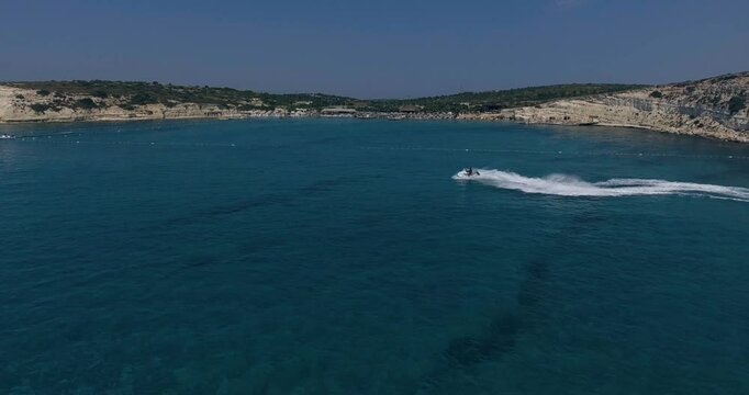 Aerial Top Down View Shot of a Person Jet Skiing in Circles. Beautiful Blue Oceanic Waters and Sun is Shining. 