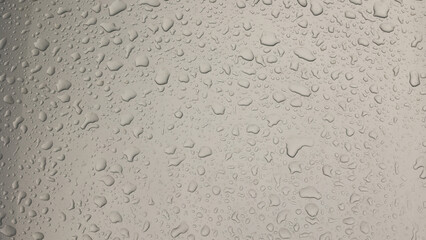 Silver car hood in raindrops. close up