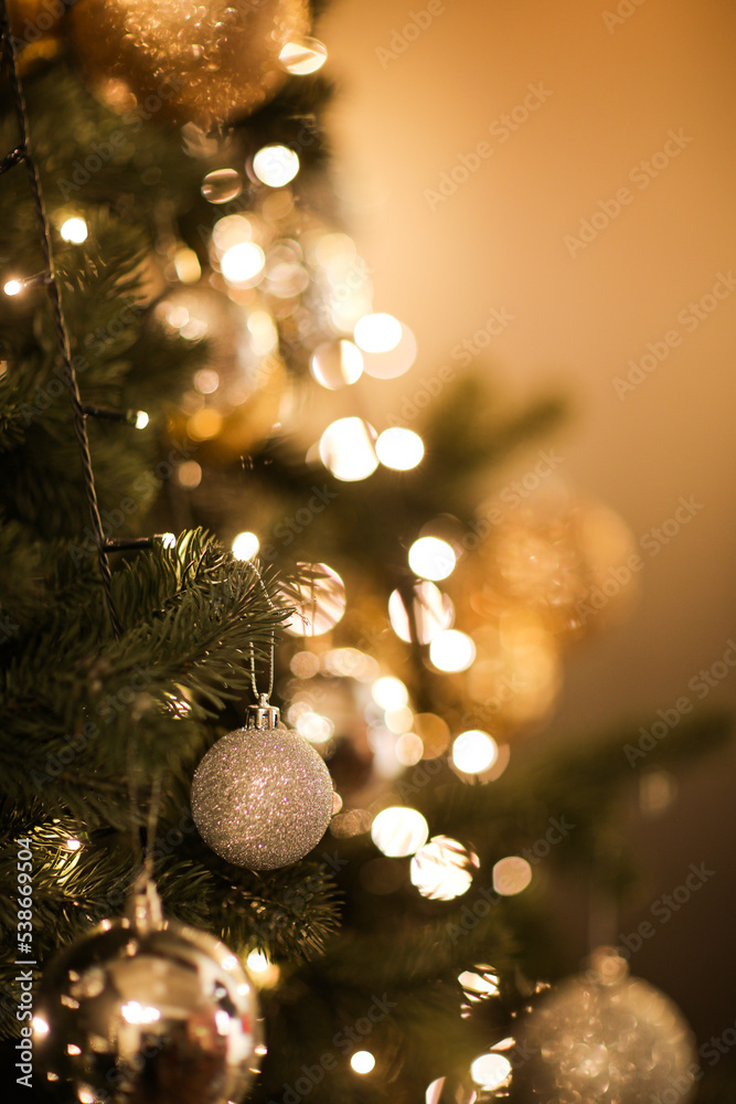 Sticker close up view of beautiful fir branches with shiny golden bauble or ball, xmas ornaments and lights,