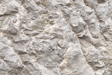 Rough gray rock wall with jagged stone boulder texture