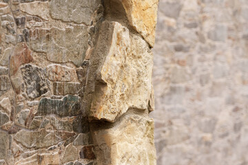 Decorative stone on the edge of dirty rock wall of the house