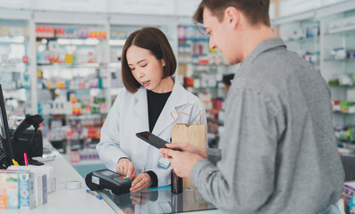 The doctor prescribes the pills according to the customer  prescription.Business, pharmacy, professional health care.An adult customer stands to pay at the pharmacy counter.