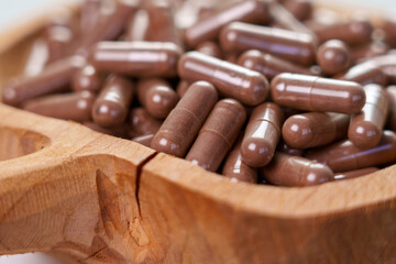 Vitamin nutritional supplement capsules in a wooden rustic container. Dietary pills