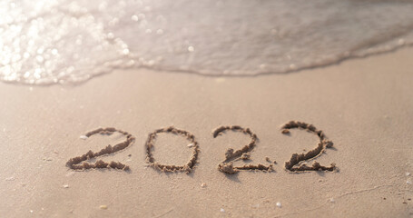 The numbers 2022 are washed away by the sea waves of the Persian Gulf. The concept of a change of years. Banner