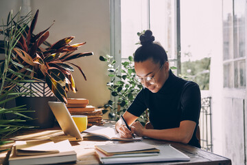 Beautiful young woman making notes and smiling while sitting at her working place in office