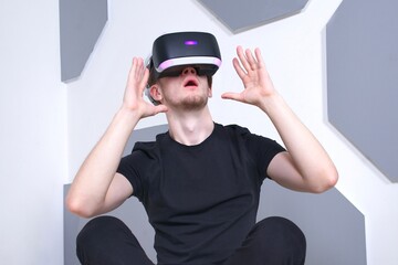 Portrait of happy young handsome man, positive smiling guy using, wearing a modern device virtual reality headset mask or 3D, AR, VR glasses, playing the game. People and technology metaverse concept