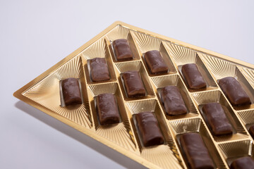Brown chocolate candies in a golden tray on a white background.